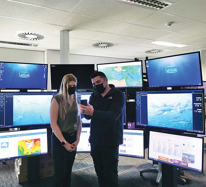 Photo of Luke Cordwell sharing information with a colleague using an app he has developed for use at Tassal, where he works. Photo: Supplied