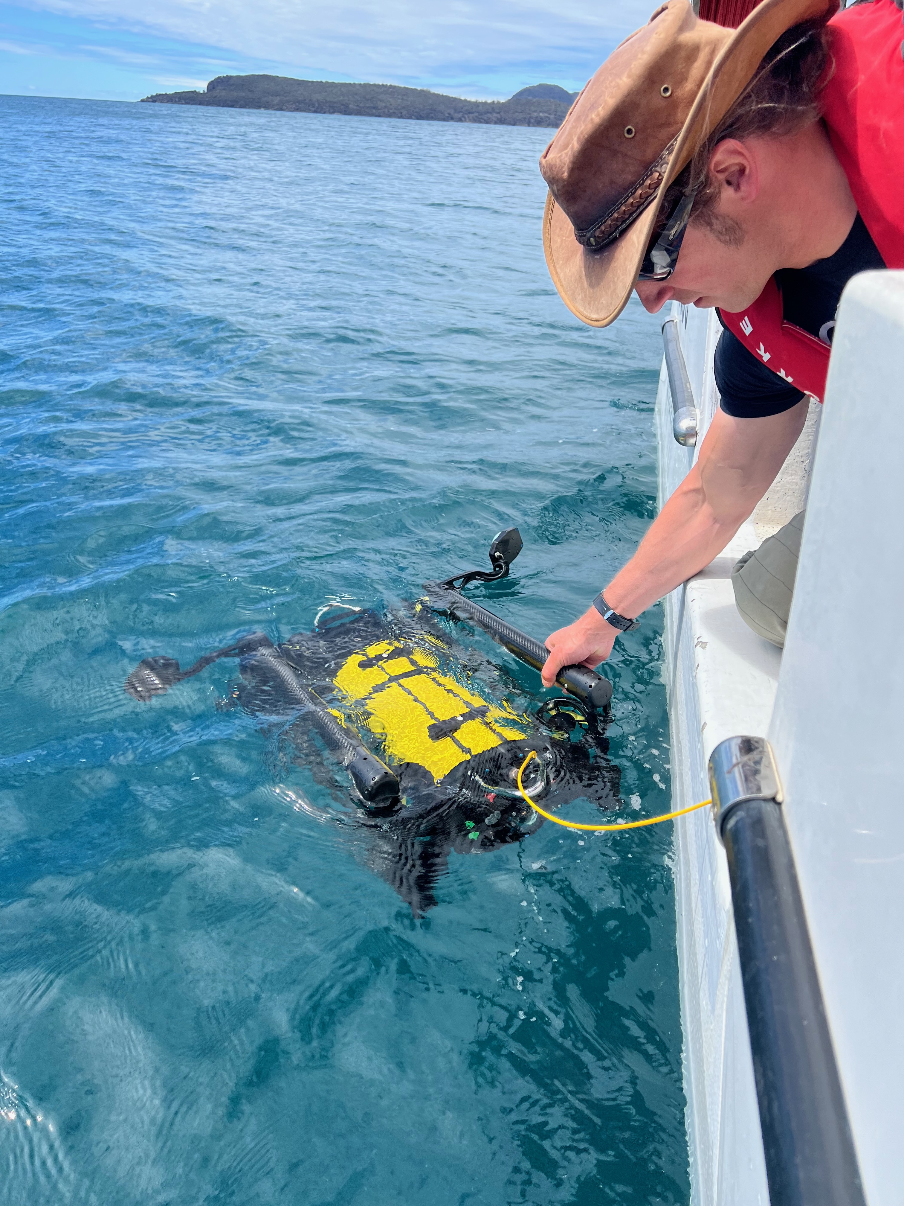 A researcher lowers an ROV into the water. Photo: IMAS 