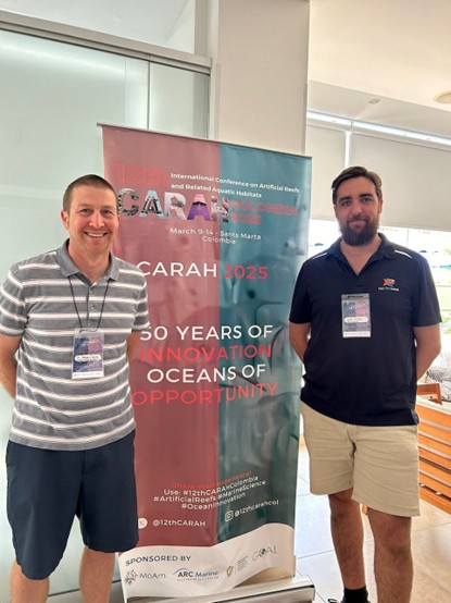 Two men standing in front of sign reading CARAH 2025